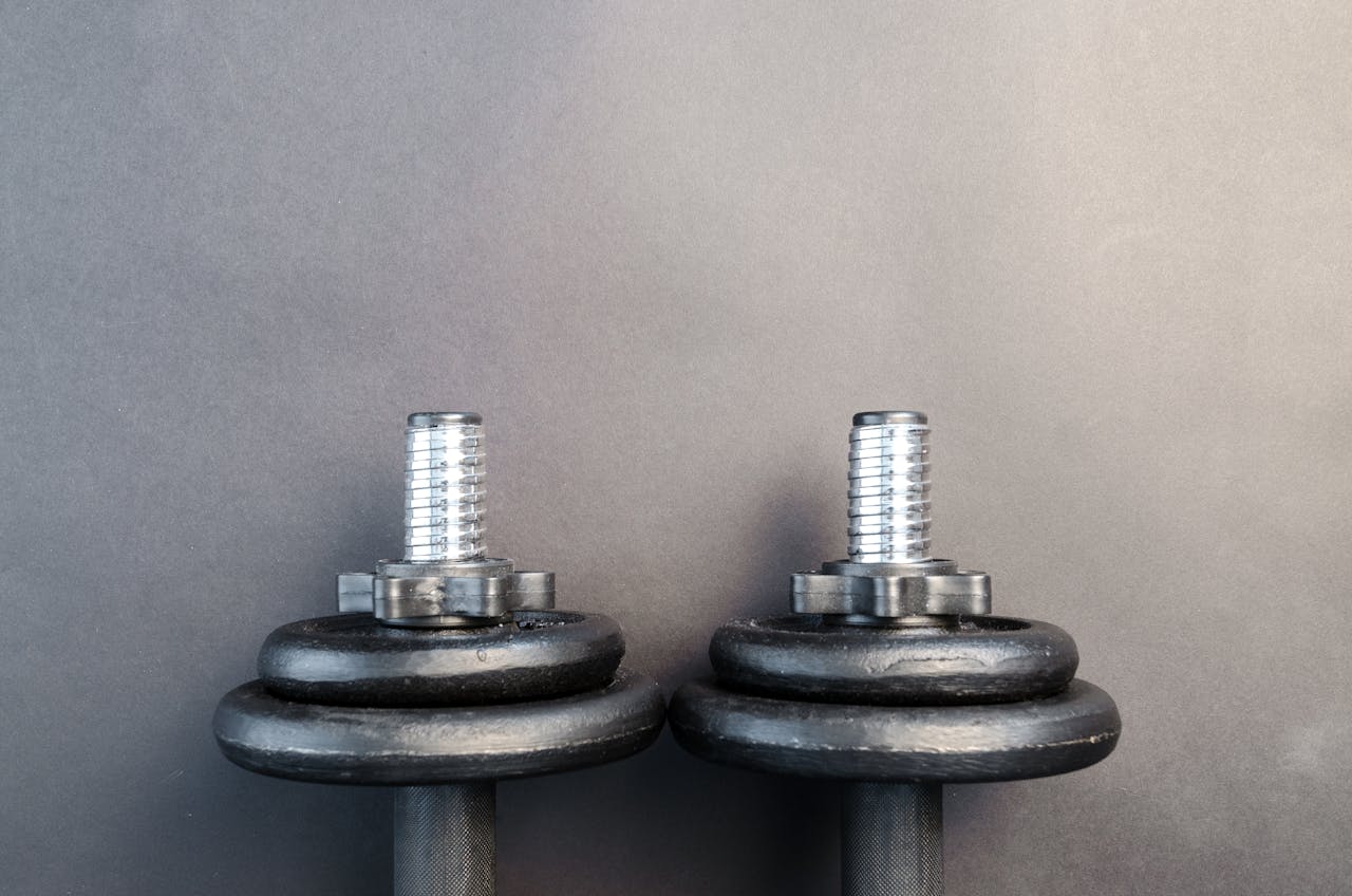 Close-up of two iron dumbbells on a gray background, perfect for strength training images.
